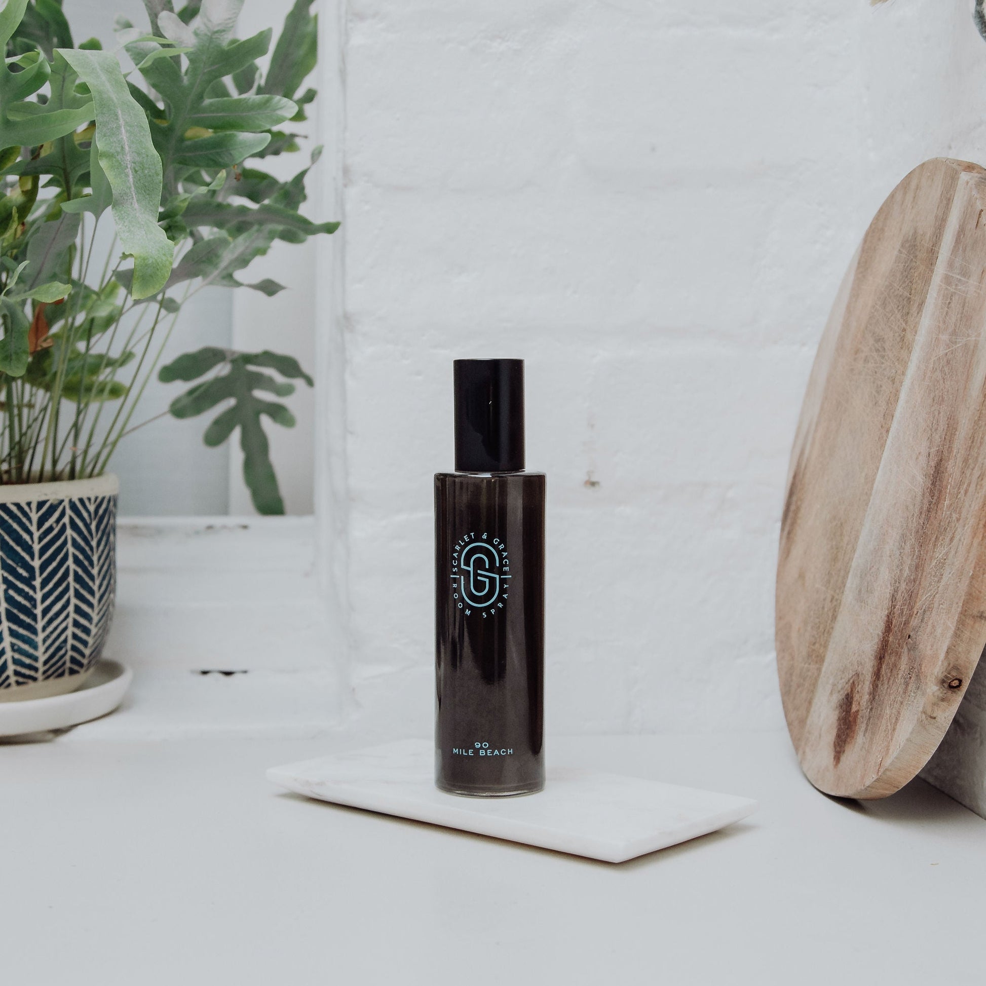 Scarlet & Grace 200ml 90 Mile Beach room spray styled on a white marble tray with greenery and timber accents

